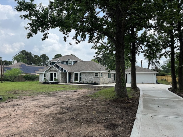 craftsman-style home with a front lawn, driveway, stone siding, and fence