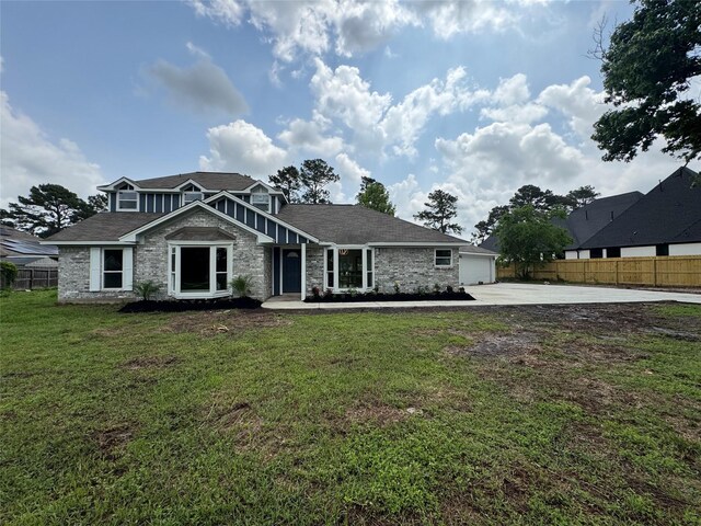 craftsman house featuring driveway, stone siding, a front yard, fence, and a garage
