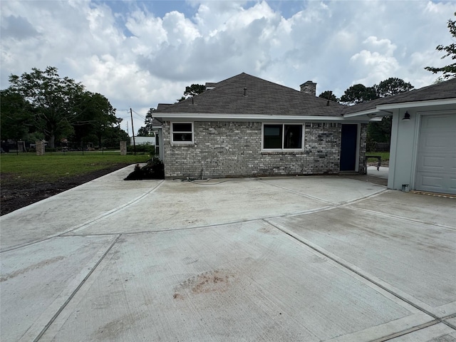 back of house with a chimney, a shingled roof, and brick siding