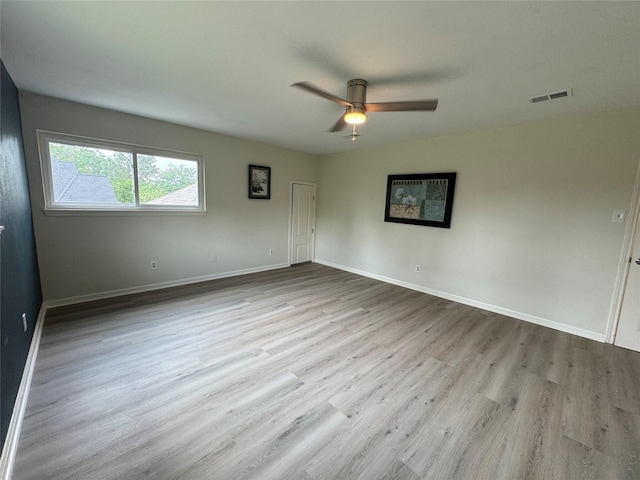unfurnished room with baseboards, visible vents, wood finished floors, and a ceiling fan