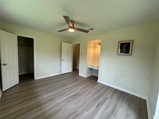 unfurnished bedroom with wood finished floors, visible vents, a closet, and baseboards