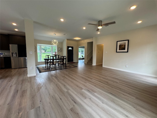 living area featuring baseboards, recessed lighting, light wood-type flooring, and stairway