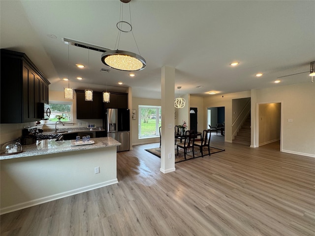 kitchen with light stone countertops, a sink, stainless steel appliances, and a healthy amount of sunlight