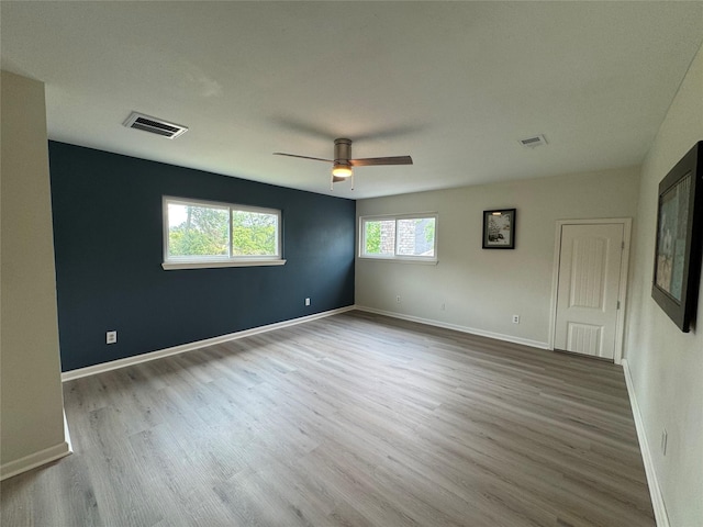 spare room featuring a ceiling fan, visible vents, wood finished floors, and baseboards