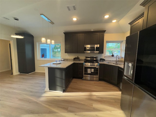 kitchen featuring appliances with stainless steel finishes, light wood finished floors, a sink, visible vents, and a peninsula