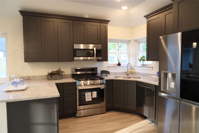kitchen with recessed lighting, a sink, stainless steel appliances, light stone counters, and light wood-style flooring