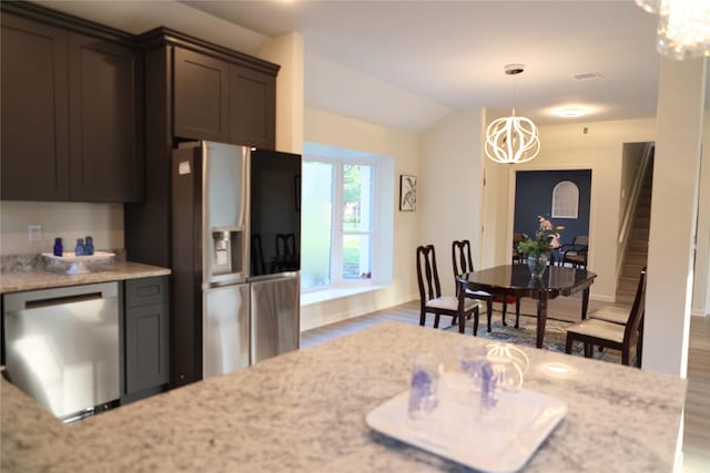 kitchen featuring light stone countertops, stainless steel appliances, an inviting chandelier, and wood finished floors