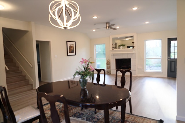 dining room featuring recessed lighting, a tile fireplace, stairway, wood finished floors, and ceiling fan with notable chandelier