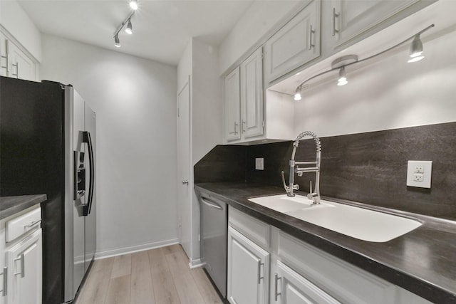 2507 Montrose Blvd Unit 50, Houston, TX 77006 - kitchen with white cabinets, stainless steel appliances, dark countertops, a sink, and light wood-type flooring