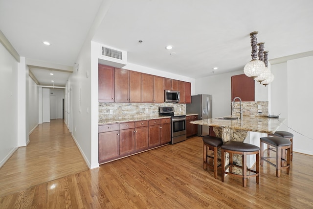 kitchen with stainless steel appliances, a sink, tasteful backsplash, visible vents, and a breakfast bar