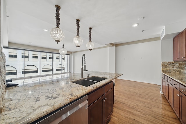 kitchen featuring stainless steel dishwasher, a sink, recessed lighting, light wood-style floors, and decorative light fixtures