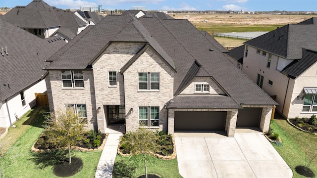 view of front of home featuring brick siding, driveway, a shingled roof, and a front lawn