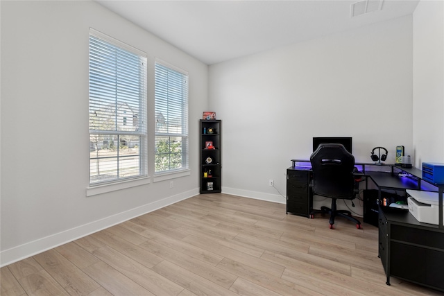 office area with baseboards, light wood-style floors, and visible vents