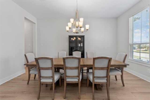 dining space with an inviting chandelier, light wood-style floors, and baseboards