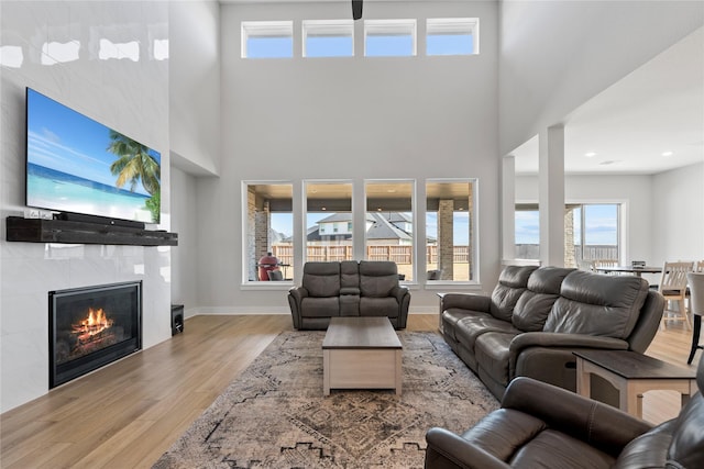 living room featuring a high ceiling, a healthy amount of sunlight, wood finished floors, and a fireplace