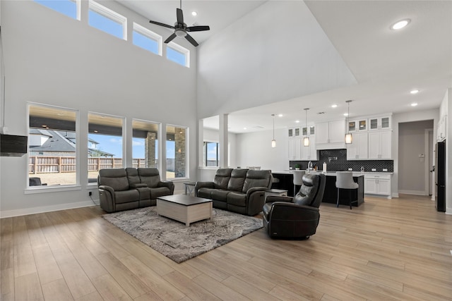 living area with light wood finished floors, plenty of natural light, a ceiling fan, and baseboards