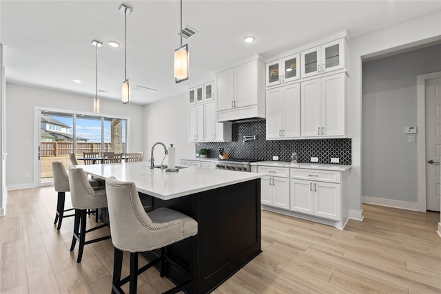 kitchen featuring white cabinetry, baseboards, decorative backsplash, and a sink