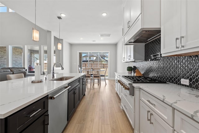 kitchen with dark cabinets, a sink, light wood-style floors, appliances with stainless steel finishes, and white cabinetry