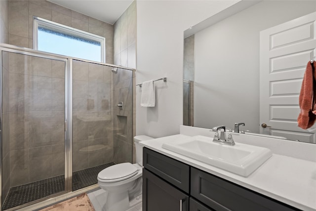 bathroom with a stall shower, vanity, and toilet
