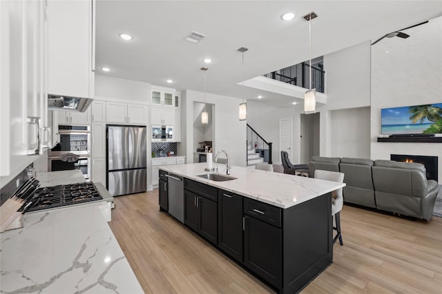 kitchen with white cabinets, stainless steel appliances, a sink, visible vents, and dark cabinetry