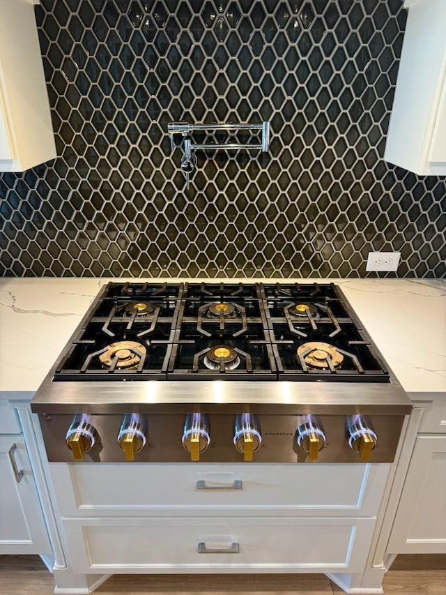 kitchen featuring white cabinets, backsplash, and light stone countertops