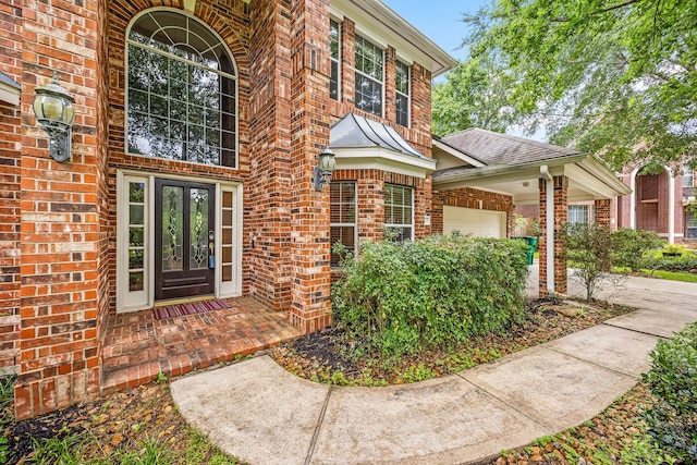 doorway to property with brick siding, a garage, and french doors