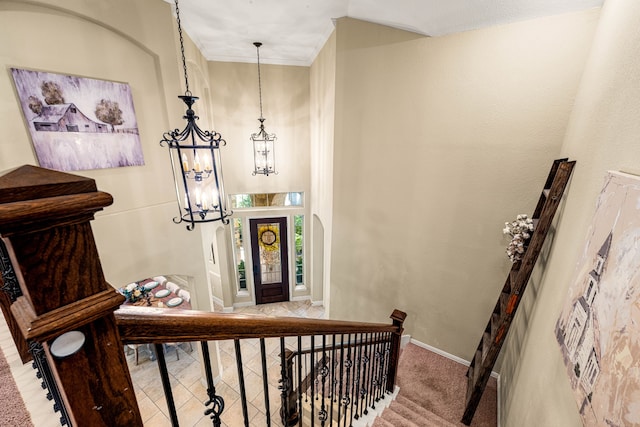 staircase featuring baseboards and a notable chandelier