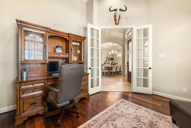 office space with a high ceiling, french doors, dark wood-style flooring, baseboards, and a notable chandelier