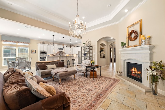 living area with a high end fireplace, visible vents, arched walkways, crown molding, and a chandelier