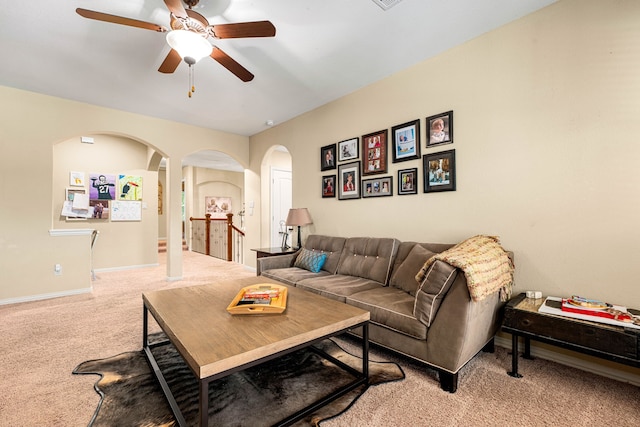 carpeted living room with a ceiling fan, baseboards, and arched walkways