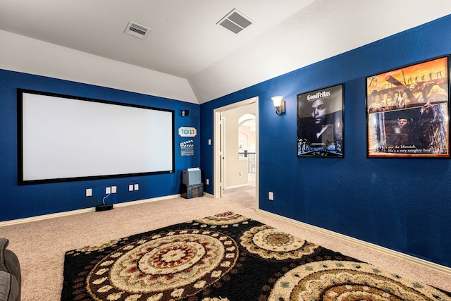carpeted home theater room with vaulted ceiling, visible vents, and baseboards