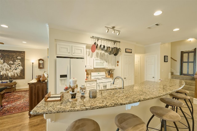 102 Capetown Slip, Conroe, TX 77356 - kitchen featuring white appliances, a kitchen bar, crown molding, light wood-style floors, and recessed lighting