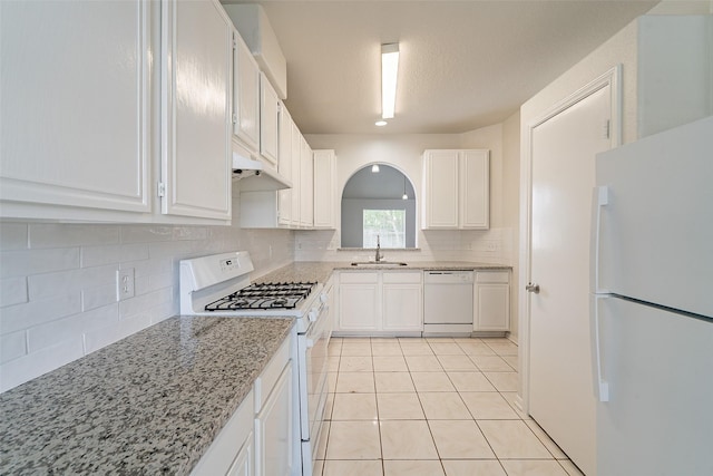 kitchen featuring tasteful backsplash, a sink, white appliances, light tile patterned floors, and white cabinetry