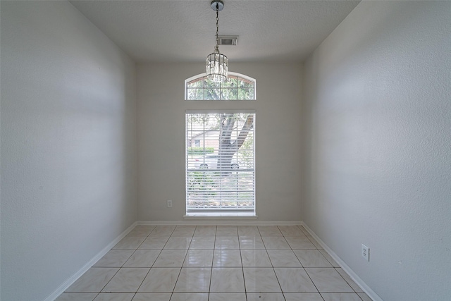 spare room with visible vents, light tile patterned floors, baseboards, a textured ceiling, and a notable chandelier