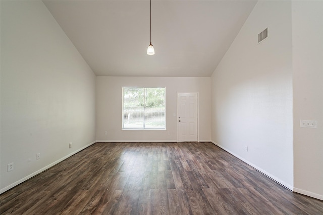 empty room with lofted ceiling, dark wood-style flooring, visible vents, and baseboards