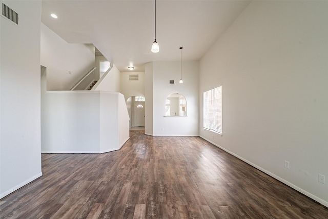foyer featuring stairway, a towering ceiling, dark wood finished floors, baseboards, and visible vents