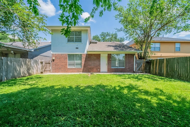 back of house featuring a fenced backyard, a gate, brick siding, and a yard