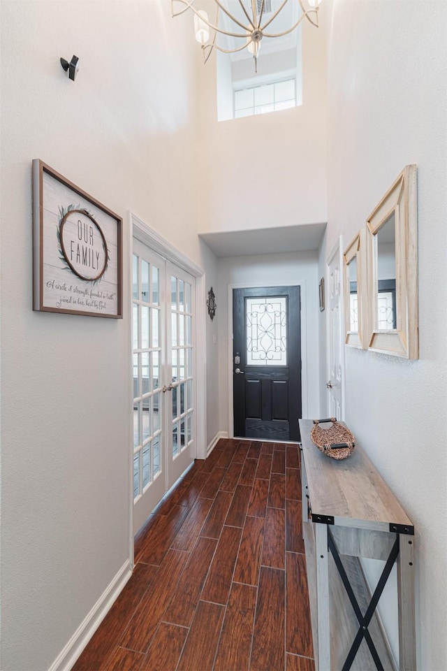 foyer entrance with french doors, a wealth of natural light, baseboards, a chandelier, and wood tiled floor