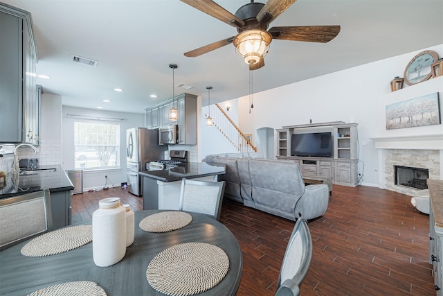 dining room with dark wood-type flooring, visible vents, ceiling fan, and a fireplace