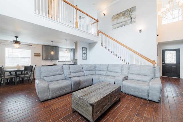 living area featuring a towering ceiling, dark wood-style floors, stairs, and ceiling fan