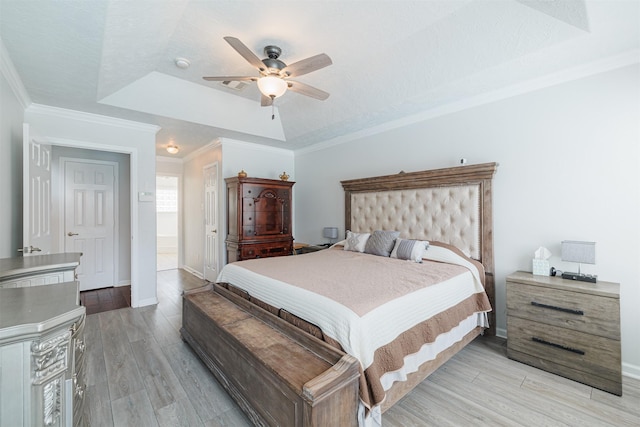 bedroom with light wood finished floors, baseboards, a tray ceiling, and ceiling fan
