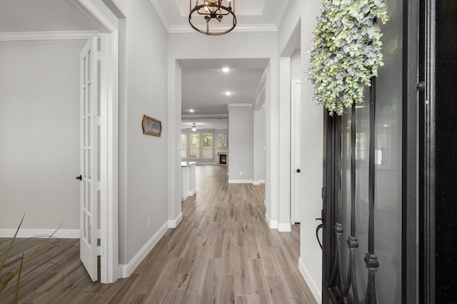 foyer entrance featuring baseboards, crown molding, an inviting chandelier, and light wood-style flooring