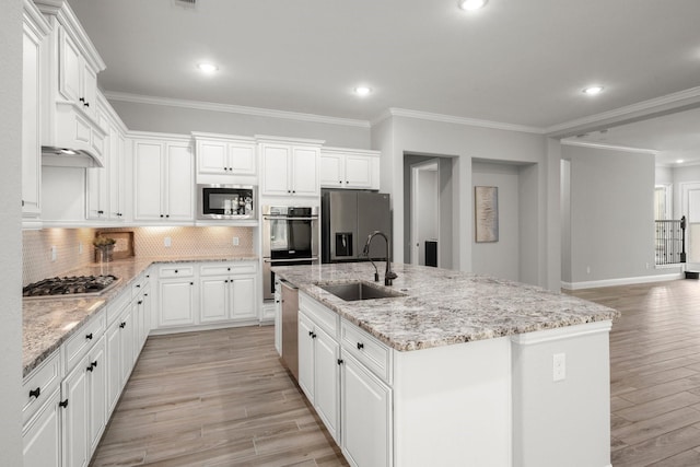 kitchen featuring a sink, an island with sink, stainless steel appliances, light wood finished floors, and backsplash