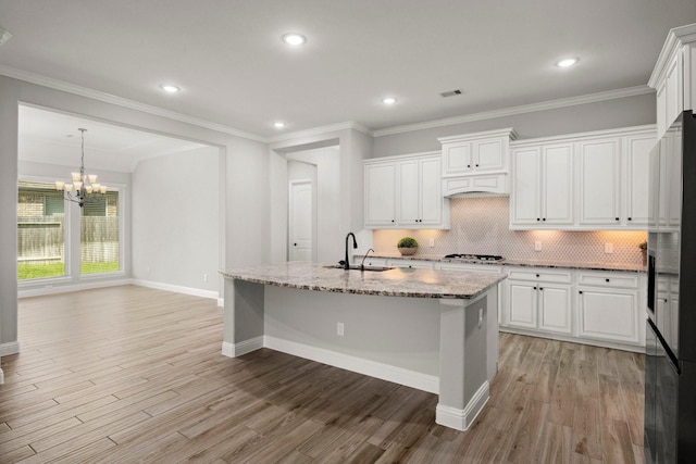 kitchen with a notable chandelier, visible vents, a sink, stainless steel refrigerator with ice dispenser, and white cabinetry