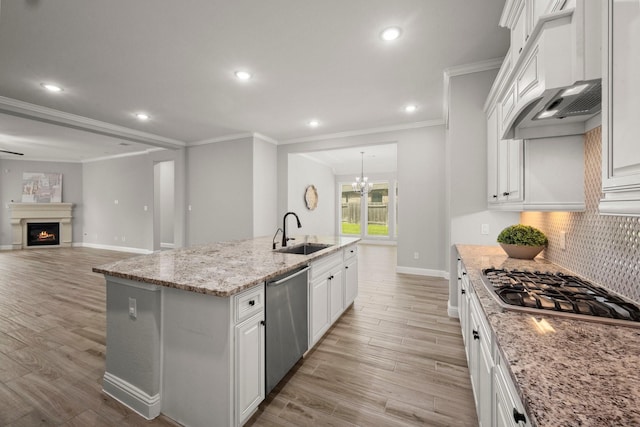 kitchen featuring crown molding, a sink, light wood-style flooring, baseboards, and appliances with stainless steel finishes