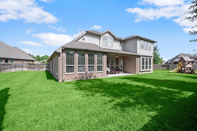 back of house with brick siding, a patio, a fenced backyard, and a playground