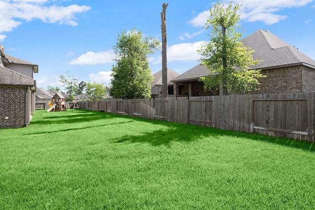 view of yard with a fenced backyard and a playground