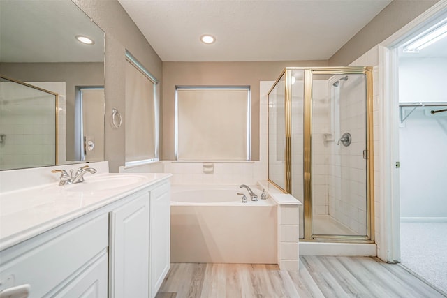10314 Friars Hl, Houston, TX 77070 - bathroom with recessed lighting, wood finished floors, a shower stall, a garden tub, and vanity
