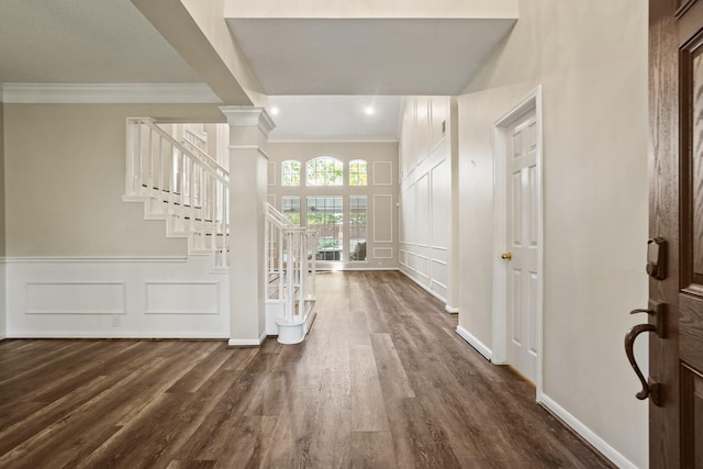 entryway featuring stairway, a decorative wall, dark wood-style floors, and ornamental molding
