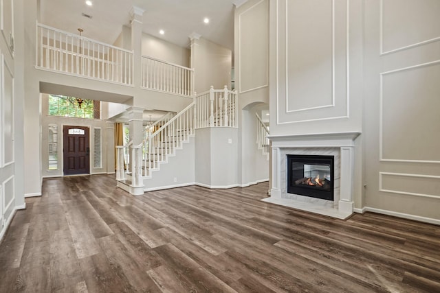 unfurnished living room with baseboards, wood finished floors, a towering ceiling, and stairs